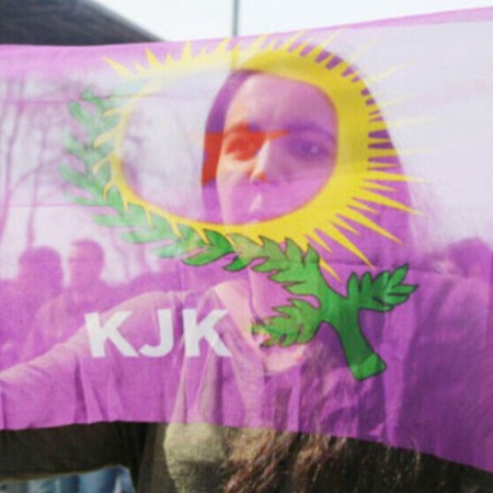 Kurdish woman holding KJK flag in front of her face